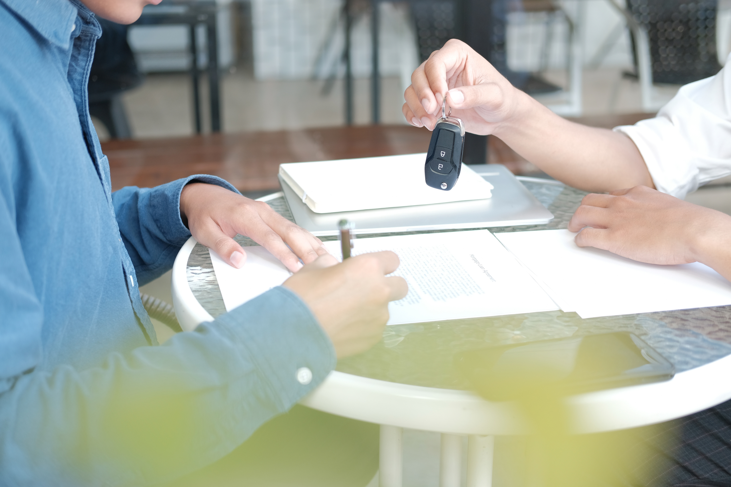 Dealer Salesman Giving Car Key To Owner. Client Signing Insurance Document Or Rental Car Lease Form