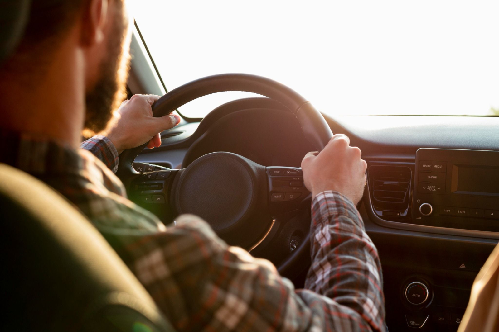 Mains sur le volant de voiture chemise carreaux